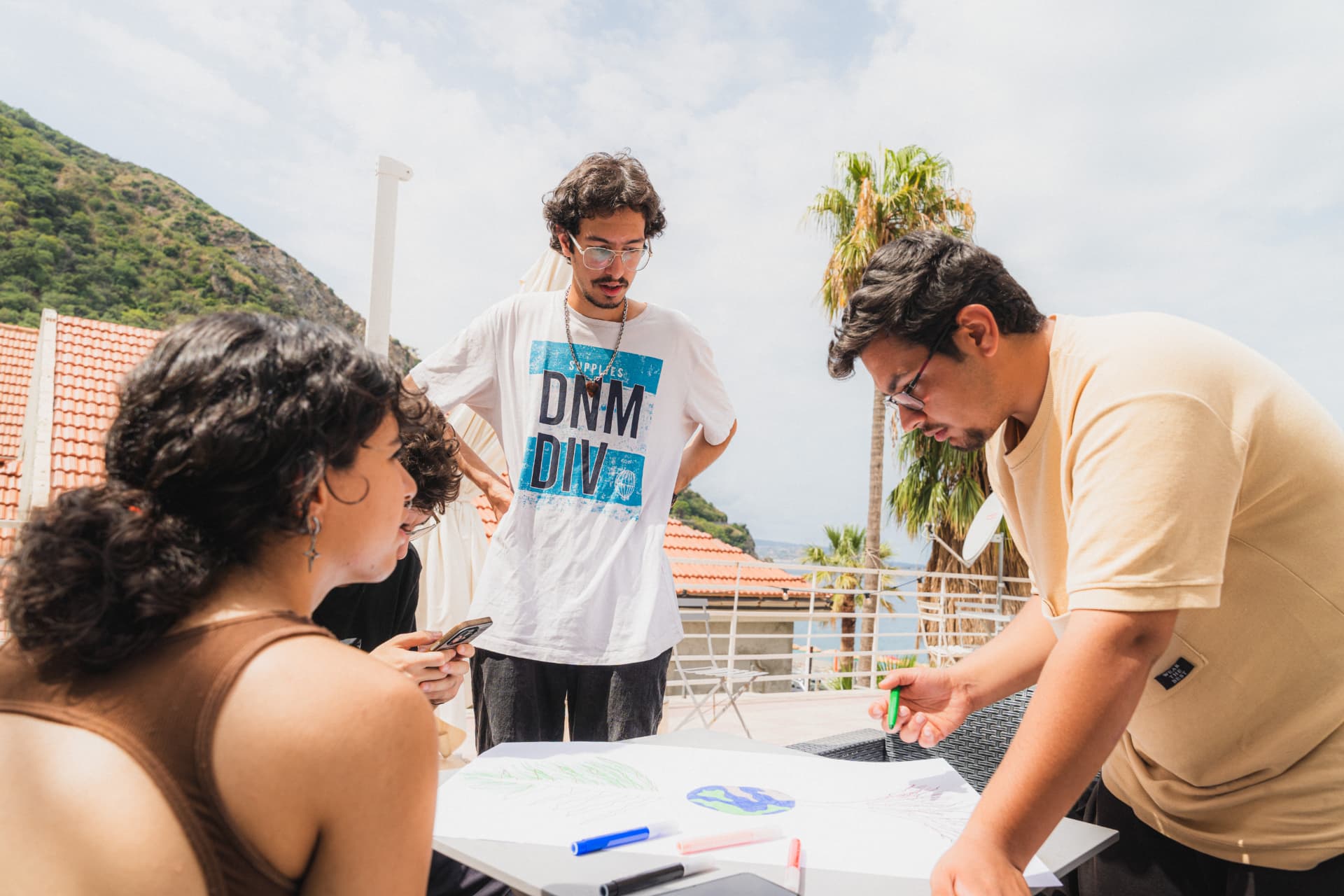 Giovani che disegnano un cartellone su una terrazza sul mare