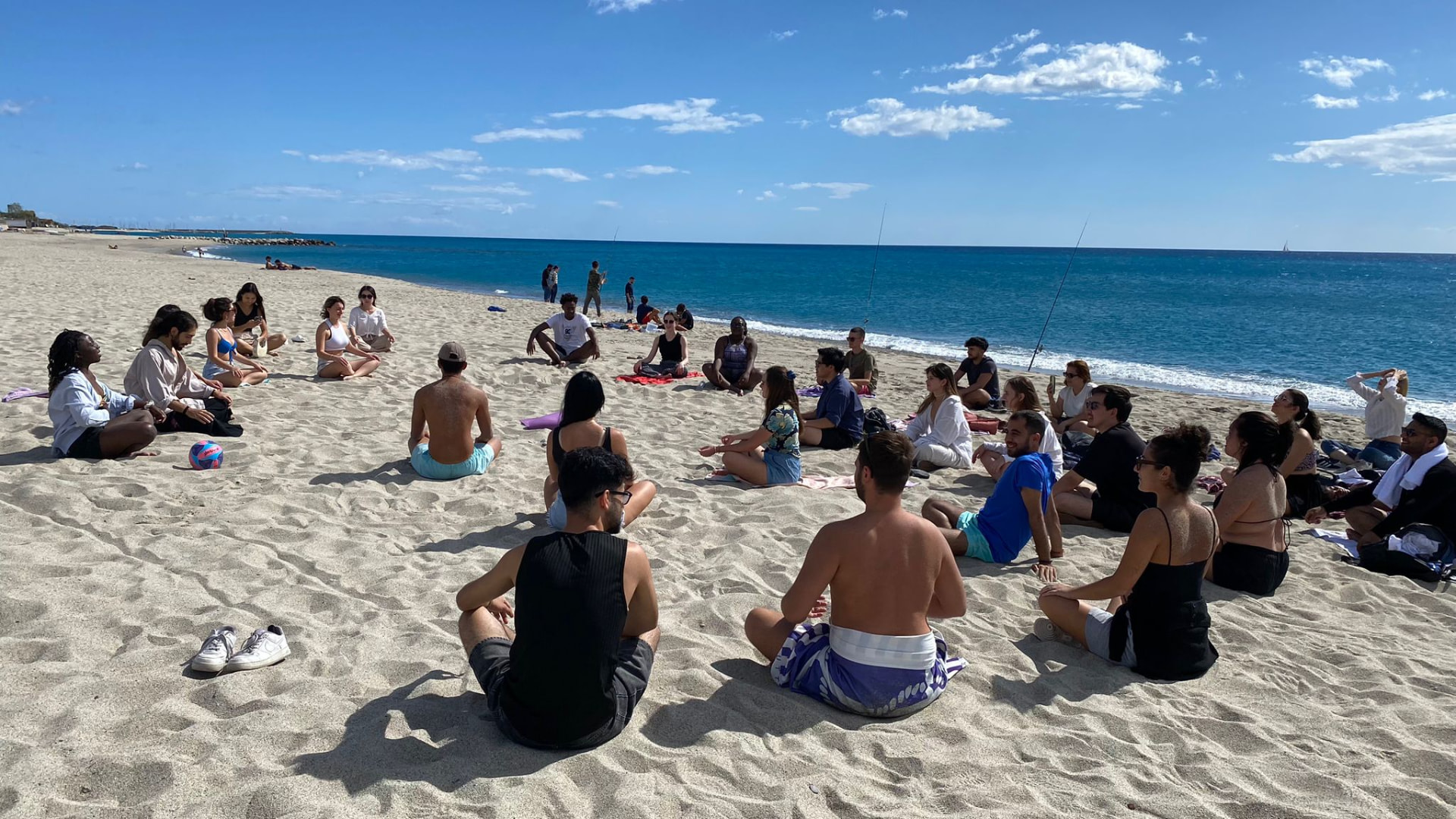 Giovani seduti in cerchio sulla spiaggia durante un laboratorio di Roccella+